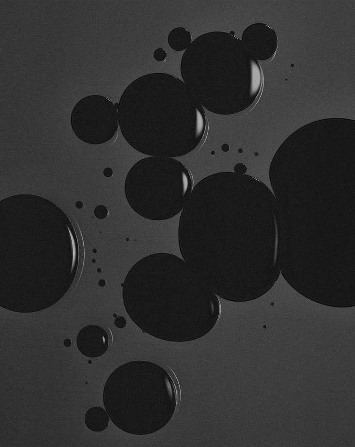 Monochromatic black and gray image of multiple circular droplets of varying sizes, some clustered together, on a dark gray background.