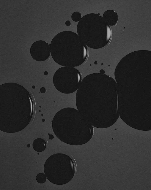 Monochromatic black and gray image of multiple circular droplets of varying sizes, some clustered together, on a dark gray background.