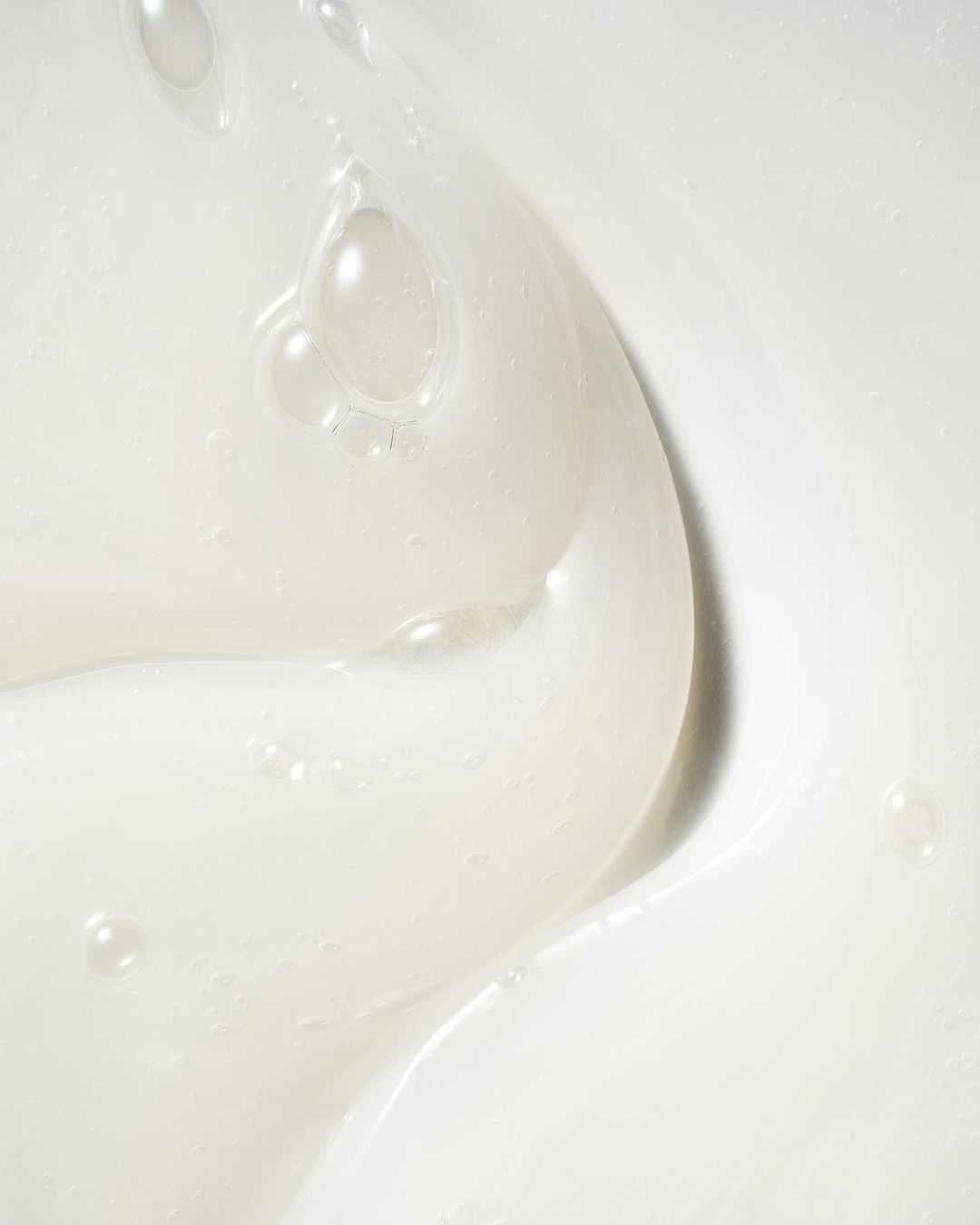Close-up of white moisturizing cream with bubbles and swirls. The texture is smooth, bright, and looks creamy and rich.