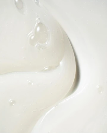 Close-up of white moisturizing cream with bubbles and swirls. The texture is smooth, bright, and looks creamy and rich.
