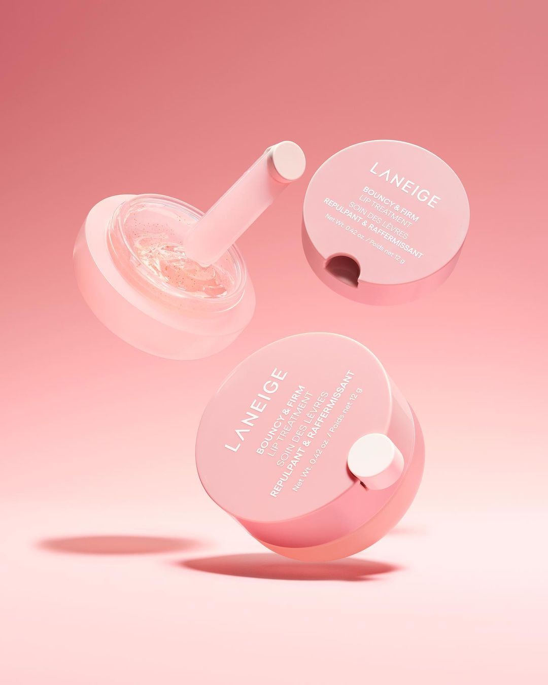 Three jars of Laneige lip treatment arranged against a pink background, showcasing a skincare product for beauty and personal care.