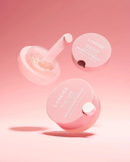 Three jars of Laneige lip treatment arranged against a pink background, showcasing a skincare product for beauty and personal care.