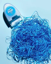 Reach Pop mint floss dispenser with a large pile of tangled blue floss strings on a blue background