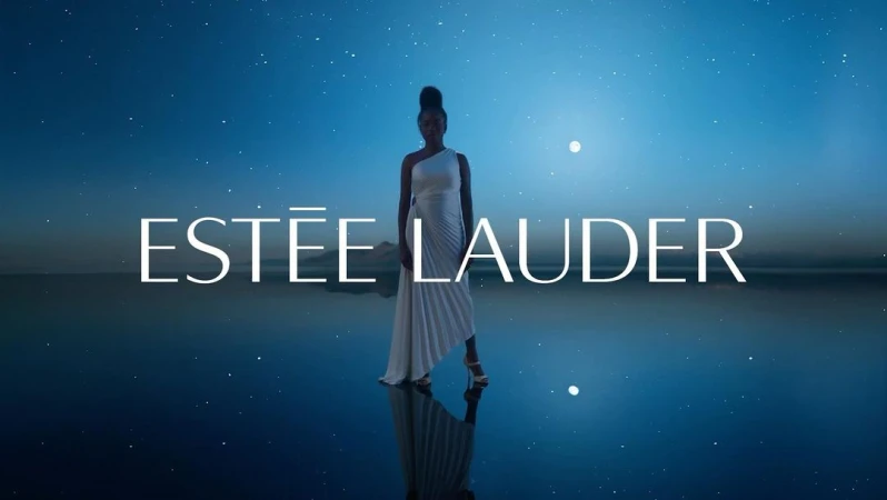 Black woman wearing a white one-shoulder dress standing on a reflective surface under a starry night sky