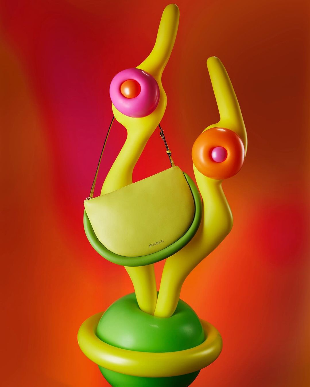 Stylish chartreuse purse with a curved shape on a decorative yellow stand with orange and pink accents against a pink and orange background.