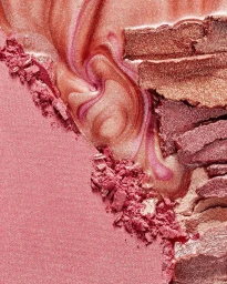 Macro view of textured pink pressed powder and shimmering liquid cosmetic swatches.