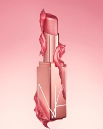 Rose gold lipstick product shot with glossy pink cream swirling around the metallic case against a soft pink background.