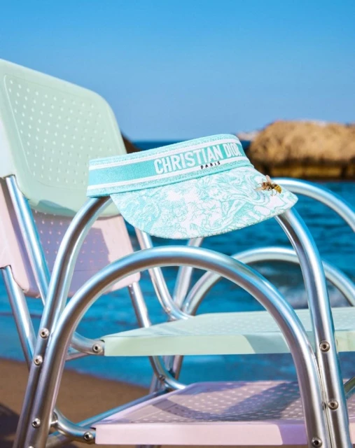 Designer visor on a beach chair with ocean and sky background, showcasing fashion accessory and summer vacation vibes on a sunny day.