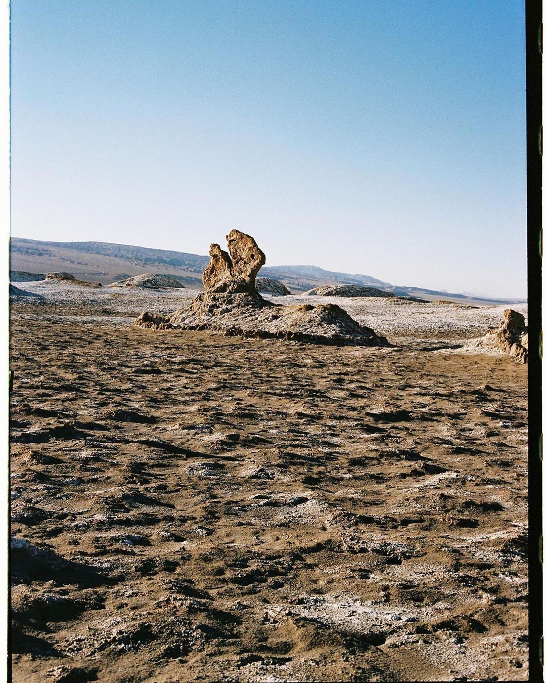 Dramatic desert landscape with rock formations under a clear blue sky, showcasing nature's sculpture in a remote and arid environment.
