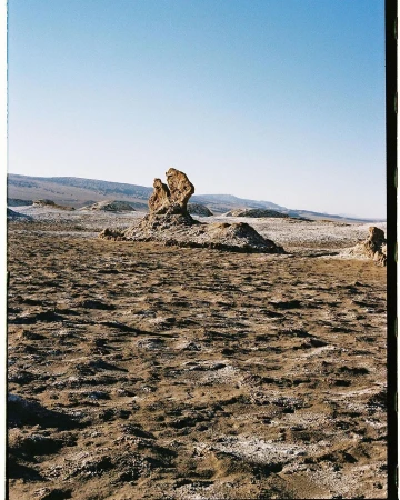 Dramatic desert landscape with rock formations under a clear blue sky, showcasing nature's sculpture in a remote and arid environment.