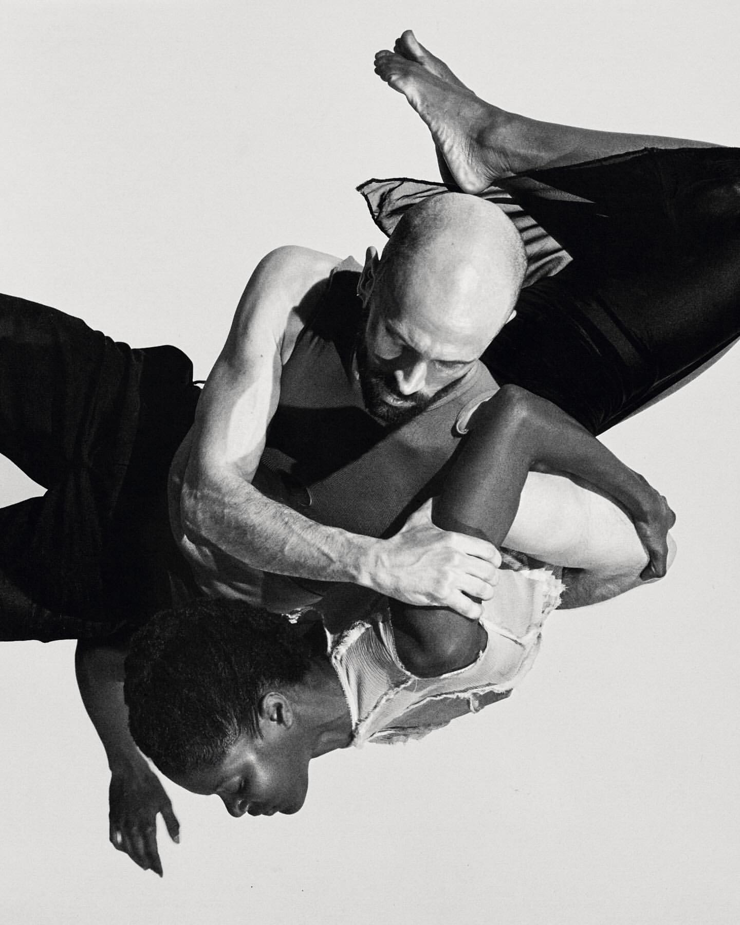 Black and white studio shot of two people, an adult female and an adult male, embracing in an intimate pose against a white backdrop.