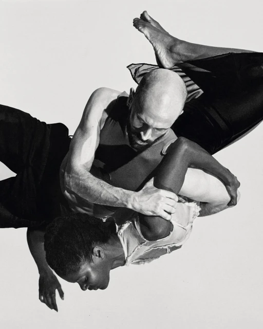 Black and white studio shot of two people, an adult female and an adult male, embracing in an intimate pose against a white backdrop.
