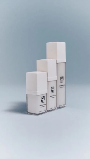 Three white cosmetic containers are arranged in ascending order against a light blue backdrop, showcasing minimalist product design.