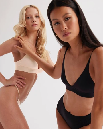 Two female models in undergarments against a white background, photographed by Lara Callahan.
