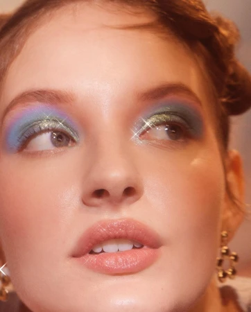 Close-up portrait of a woman wearing colourful eyeshadow and glitter with updos by photographer Lara Callahan