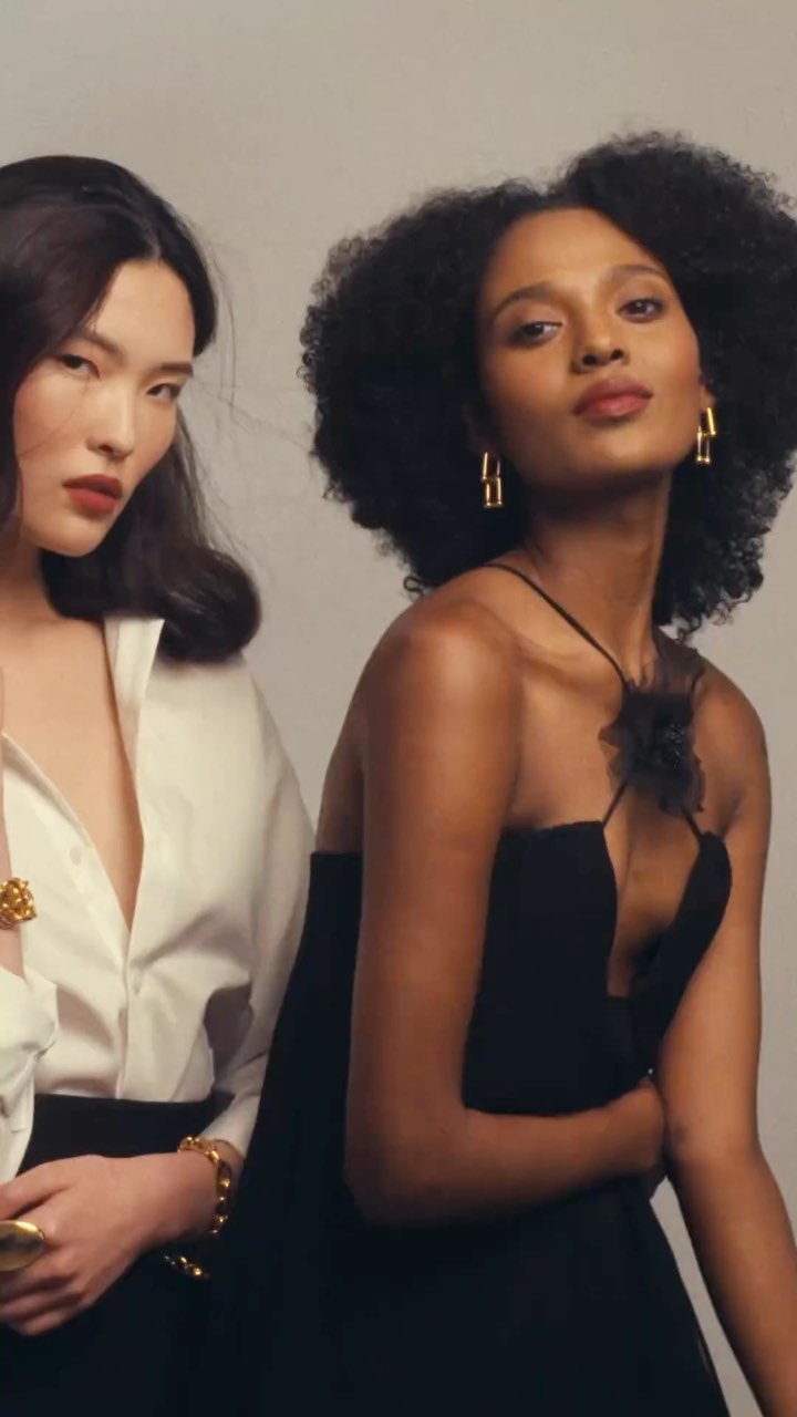 Two female models posing in studio, one in a white shirt and one in a black dress by photographer Lara Callahan
