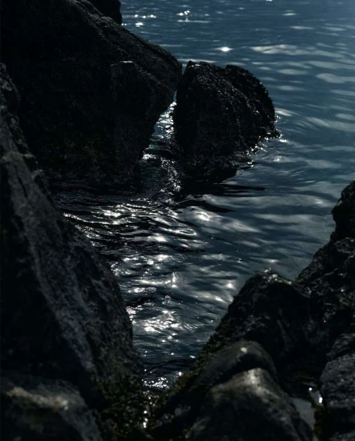 Dark rocky outcroppings framing glittering water with sunlight reflecting off ripples