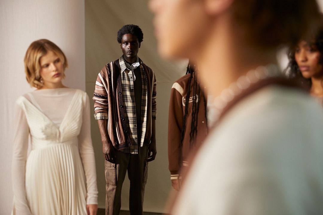 Fashion models showcase neutral-tone outfits in a studio setting. A diverse group of adults is captured with soft lighting and a neutral background.