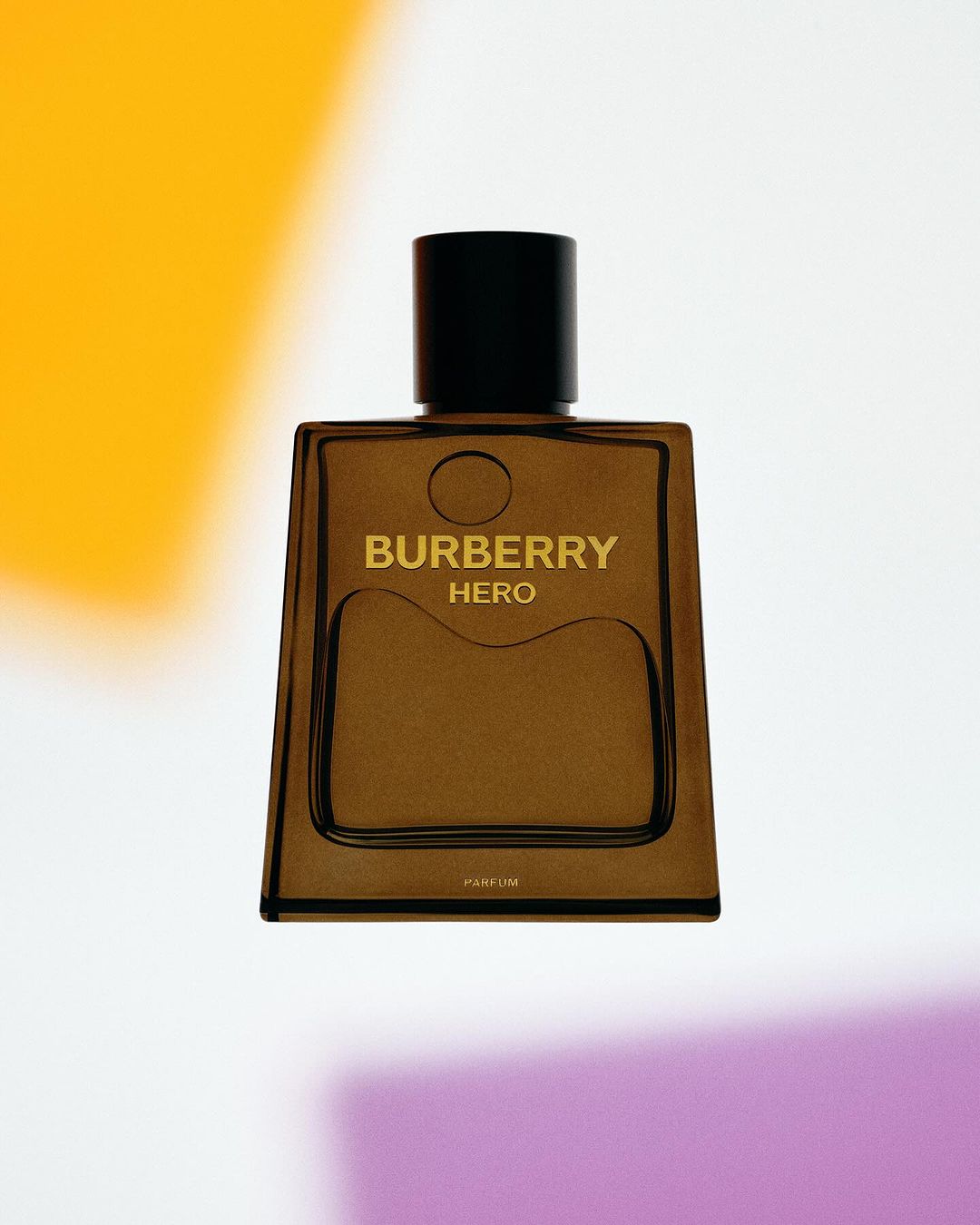 Burberry Hero Parfum bottle on a white surface, featuring a minimalist design, black cap, and transparent, brown-tinted glass.