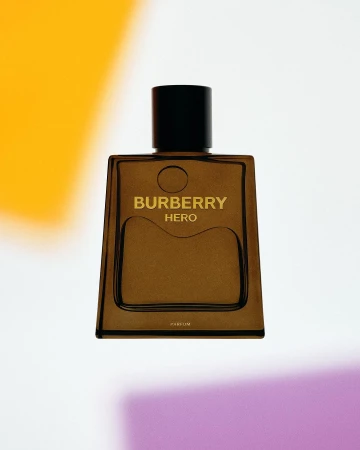 Burberry Hero Parfum bottle on a white surface, featuring a minimalist design, black cap, and transparent, brown-tinted glass.