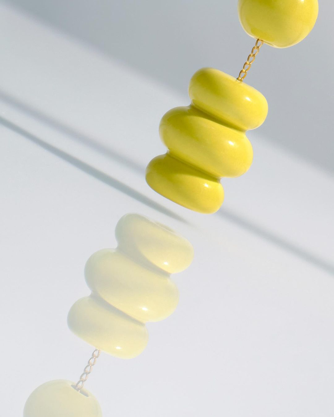 Close-up of a yellow bead necklace on a white background, creating a clean and minimalist jewelry shot with studio lighting.