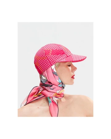 Profile portrait of a woman wearing a pink polka dot cap and a vibrant silk scarf around her neck against a plain background