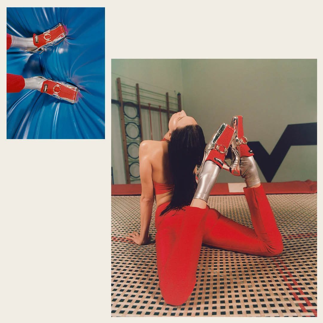 A woman in a red outfit and silver platform heels sits on a trampoline indoors with a cropped inset of the shoes on a blue surface.