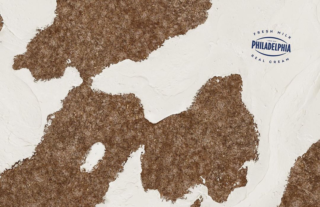 Abstract background of cream cheese and brown texture, with the Philadelphia Cream Cheese logo visible on the upper right.