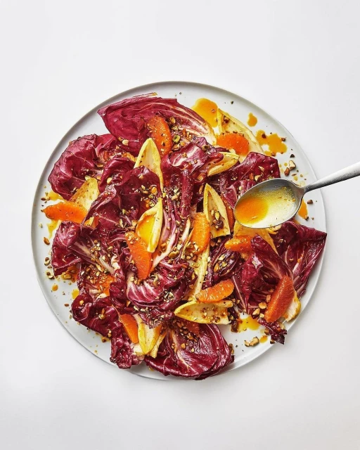 Radicchio salad with orange slices and dressing on a plate, top-down studio shot, vibrant colors, and appetizing presentation.