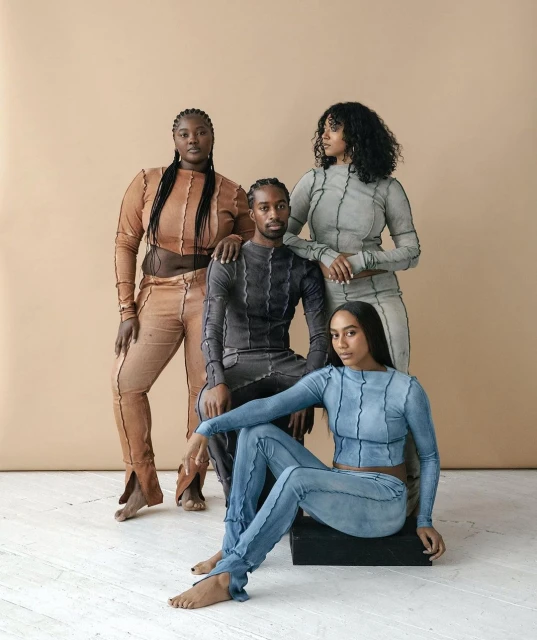 Group of four diverse fashion models in color-coordinated outfits in a studio setting, showcasing modern style and individual poses.