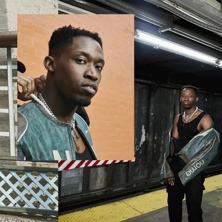 Portrait of a young African-American man in a bomber jacket and tank top standing in a subway station with yellow safety tiles.