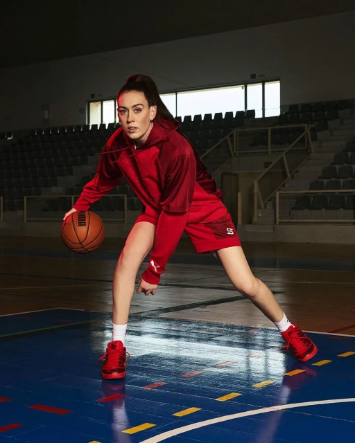 Female athlete in sportswear dribbles a basketball on an indoor court, showcasing athletic skill and a dynamic pose.
