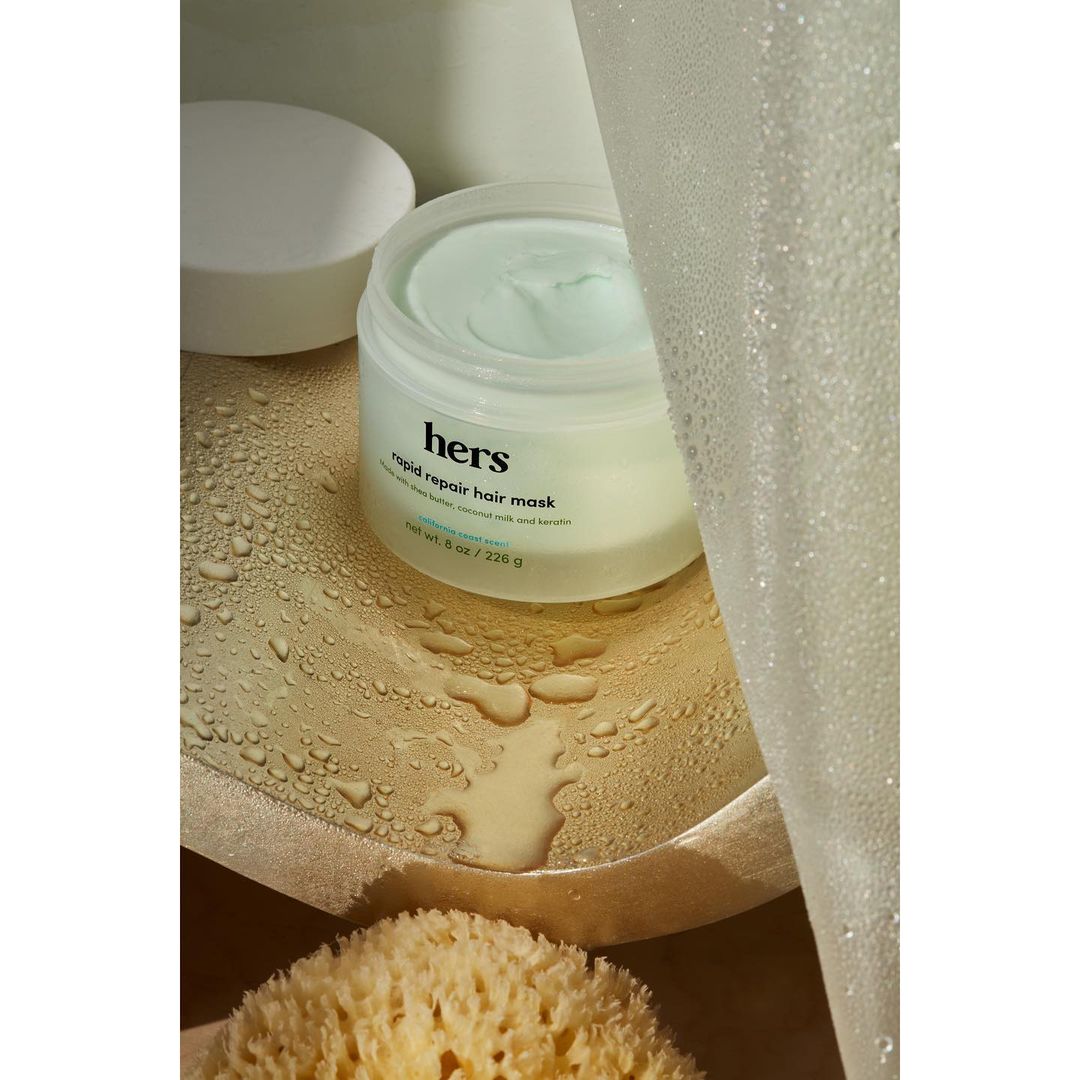 Close-up studio shot of hers rapid repair hair mask jar, complemented by a white lid and a natural sponge, set against a neutral backdrop.