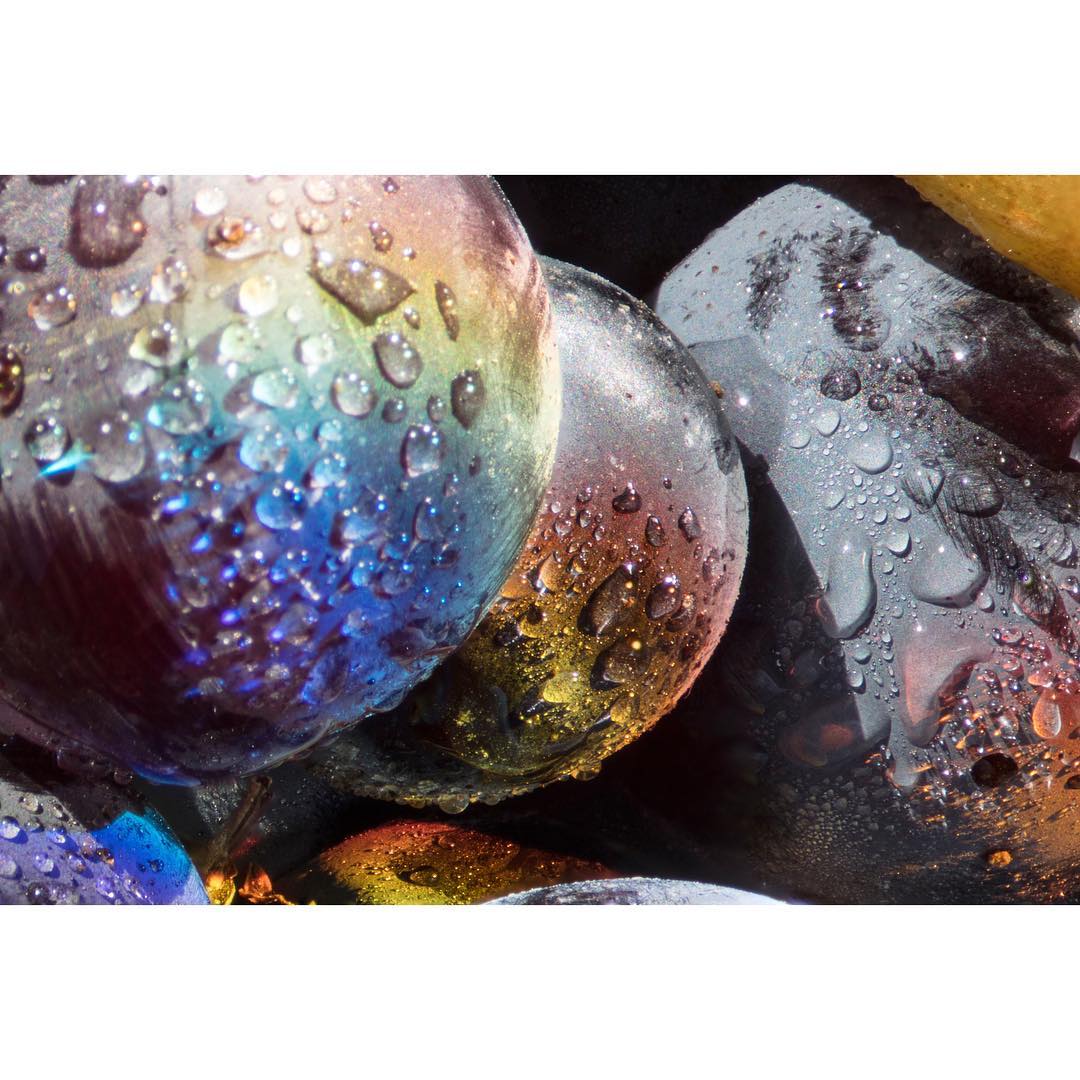 Macro shot of fresh purple grapes with water droplets, showcasing the vibrant colors and textures under bright, diffused lighting.