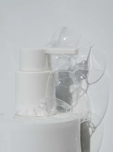 Macro shot of a white cylindrical container covered in transparent bubbles against a soft white background, creating a clean aesthetic.