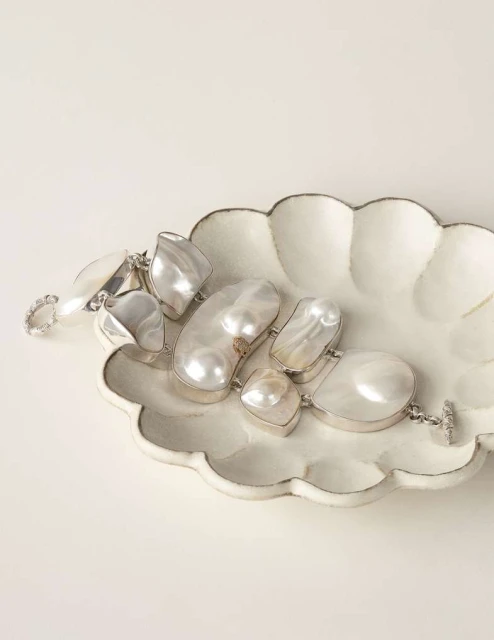 Elegant pearl bracelet on a decorative plate against a neutral backdrop, capturing its luster and unique shape, ideal for showcasing jewelry.