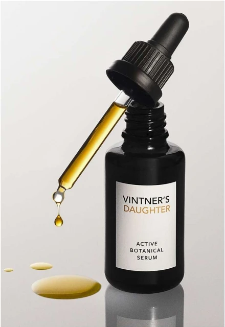 Close-up product shot of Vintner's Daughter Active Botanical Serum in a dark bottle with a dropper dispensing serum, against a white background.