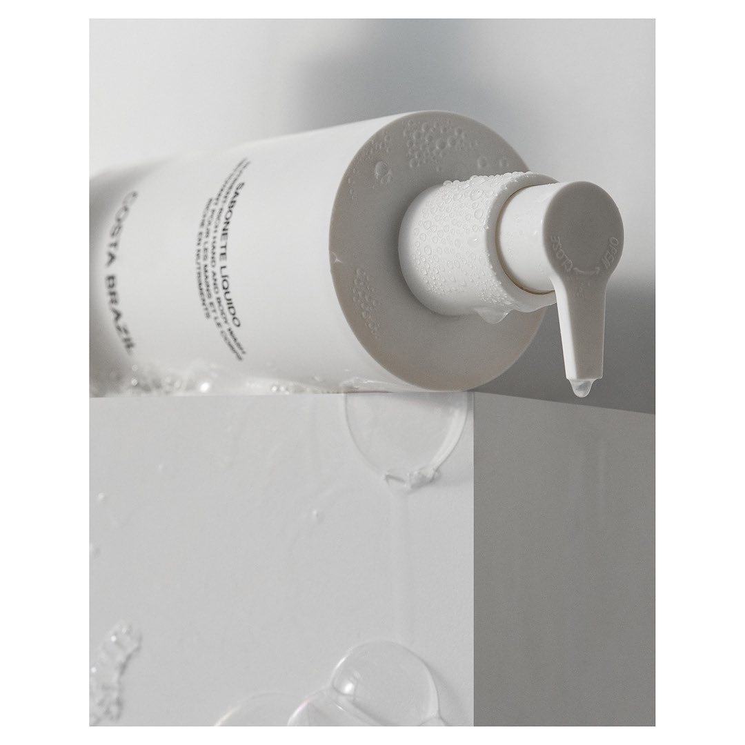 Costa Brazil Sabonete Liquido soap dispenser with water droplets, minimalist product shot, pristine white and modern presentation.
