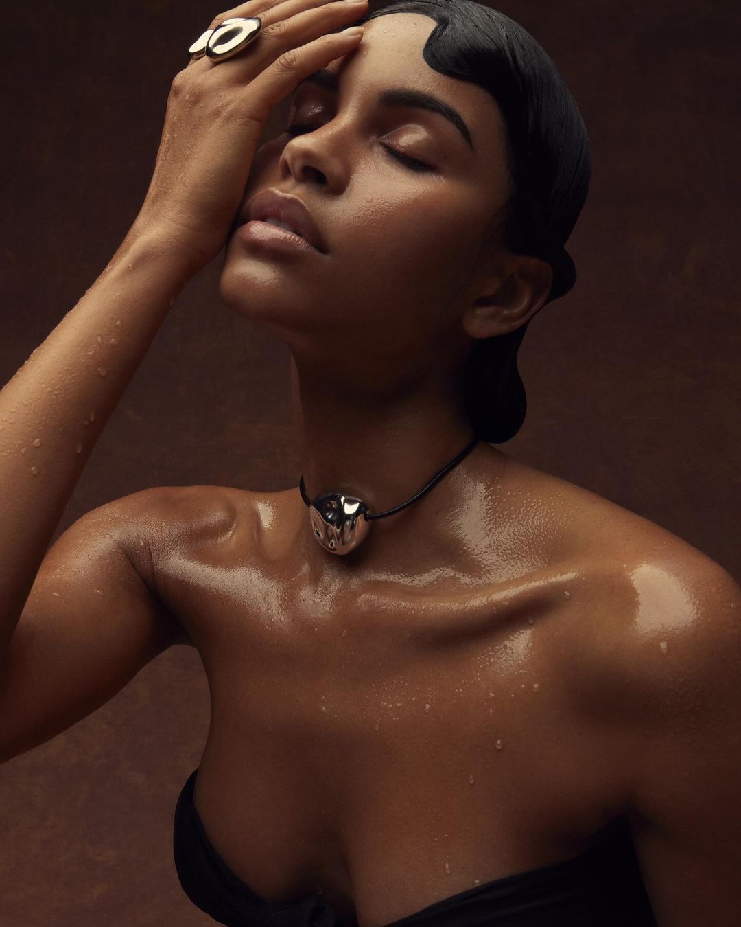 Close-up portrait of a woman with wet skin wearing a silver choker and ring, photographed by Lauren Loncar