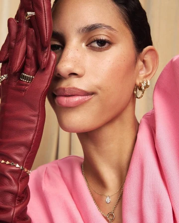 Close-up portrait of a woman wearing pink top and dark red leather gloves adorned with rings, photographed by Lauren Loncar.