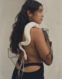 Woman in profile wearing sheer black mesh and black bottoms with a white snake draped over her shoulders by Lauren Loncar