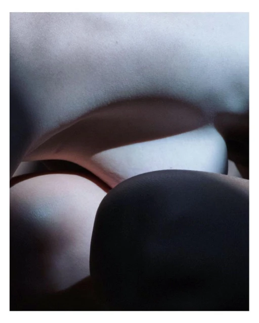 Abstract nude art photography featuring a close-up of female form with dramatic lighting, emphasizing shadows and textures on skin in a studio.