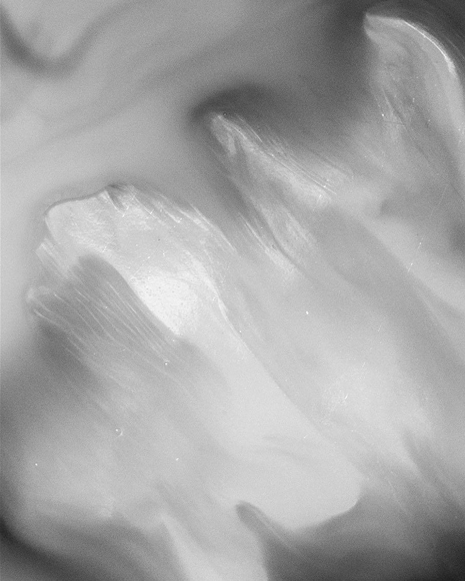 Black and white abstract background with a smooth, flowing texture and highlights, resembling paint or liquid movement.