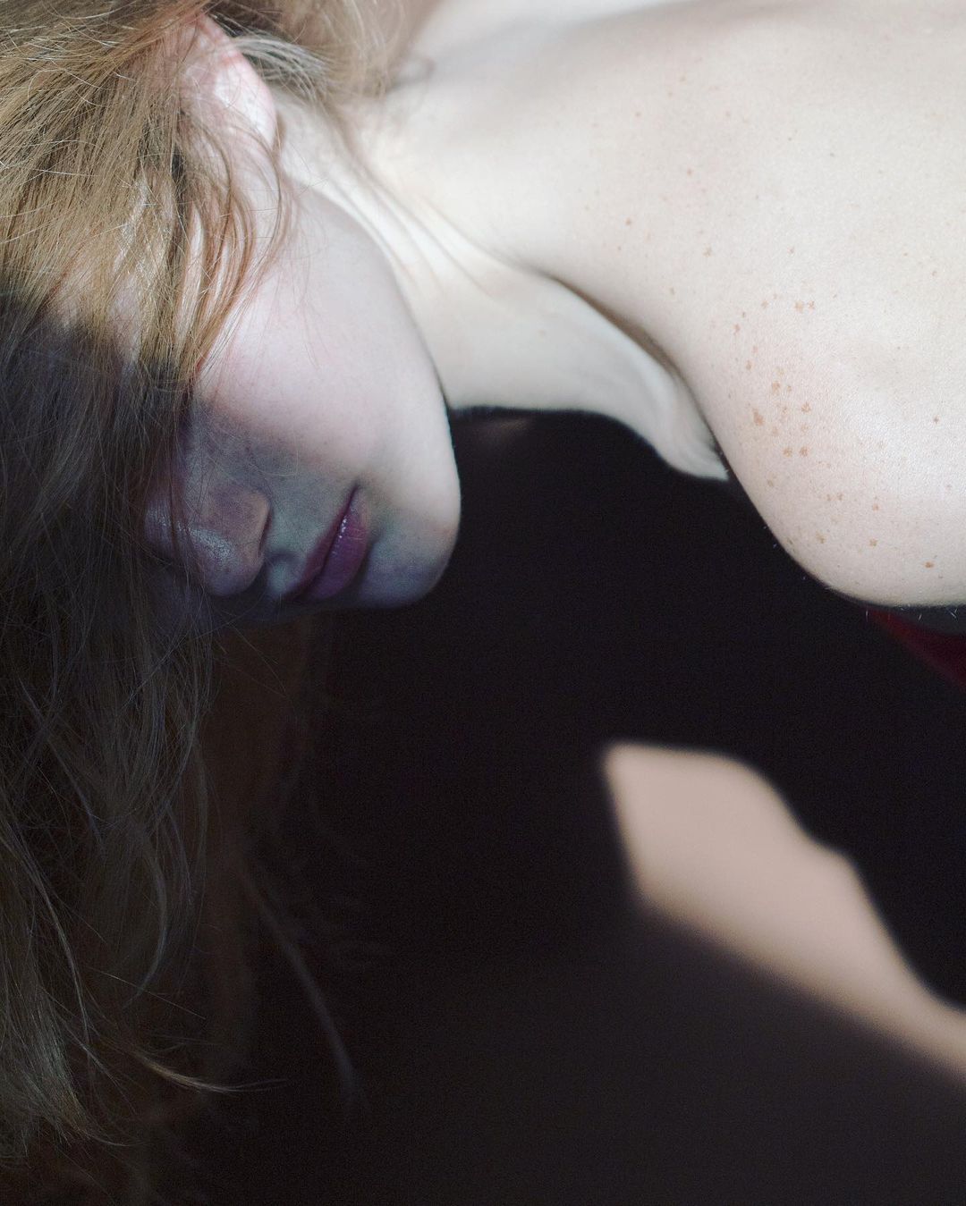 Close-up portrait of a woman with long hair and freckles on her shoulder captured by Laurent Castellani in Paris
