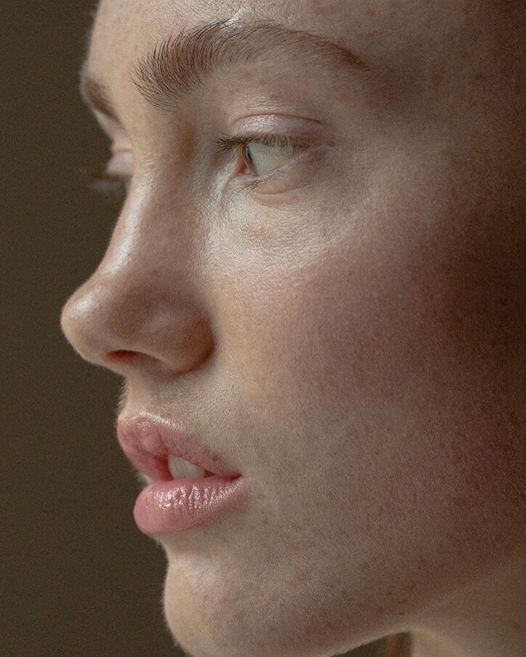Close-up portrait of a fair-skinned adult female with light-colored eyes looking off-camera in soft, diffused light, minimal makeup.