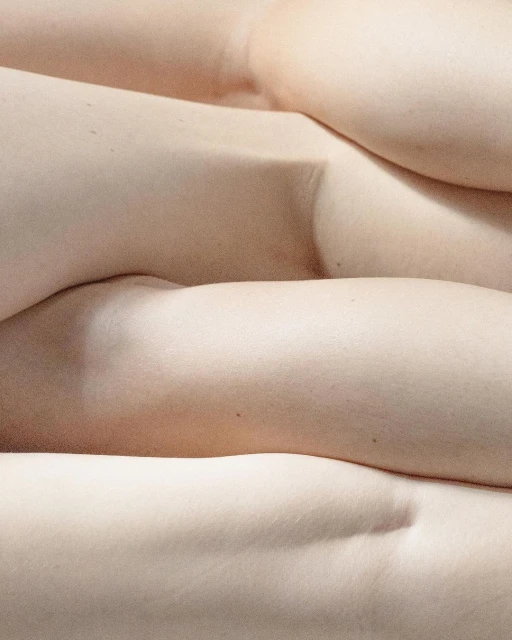 Close-up studio shot of stacked human torsos. Skin texture visible with neutral lighting. High angle and shallow depth of field.