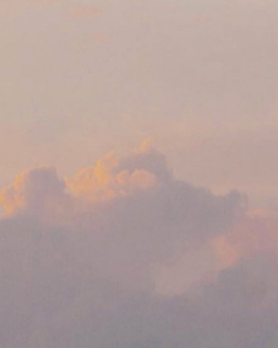 Dreamy skyscape featuring soft clouds illuminated with pastel tones of peach, pink, and lavender at golden hour.