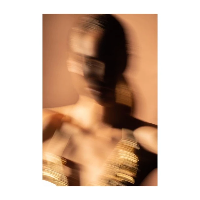 Blurred fashion photo of a dark-haired adult female model with painted face and metallic fabric. Stylish abstract beauty and design concept.