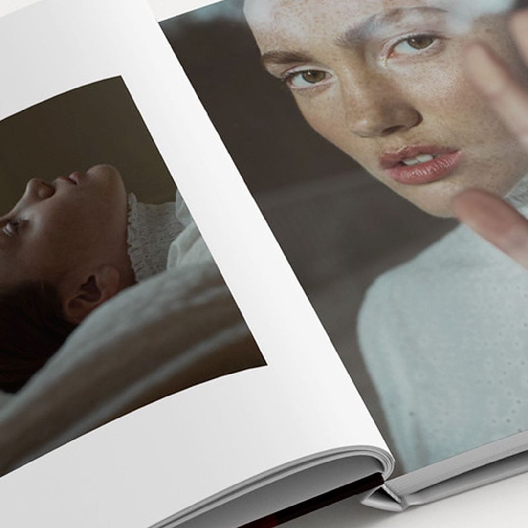 Open magazine spread featuring close-up portrait of a fair-skinned adult female looking at camera and another of a reclining person.