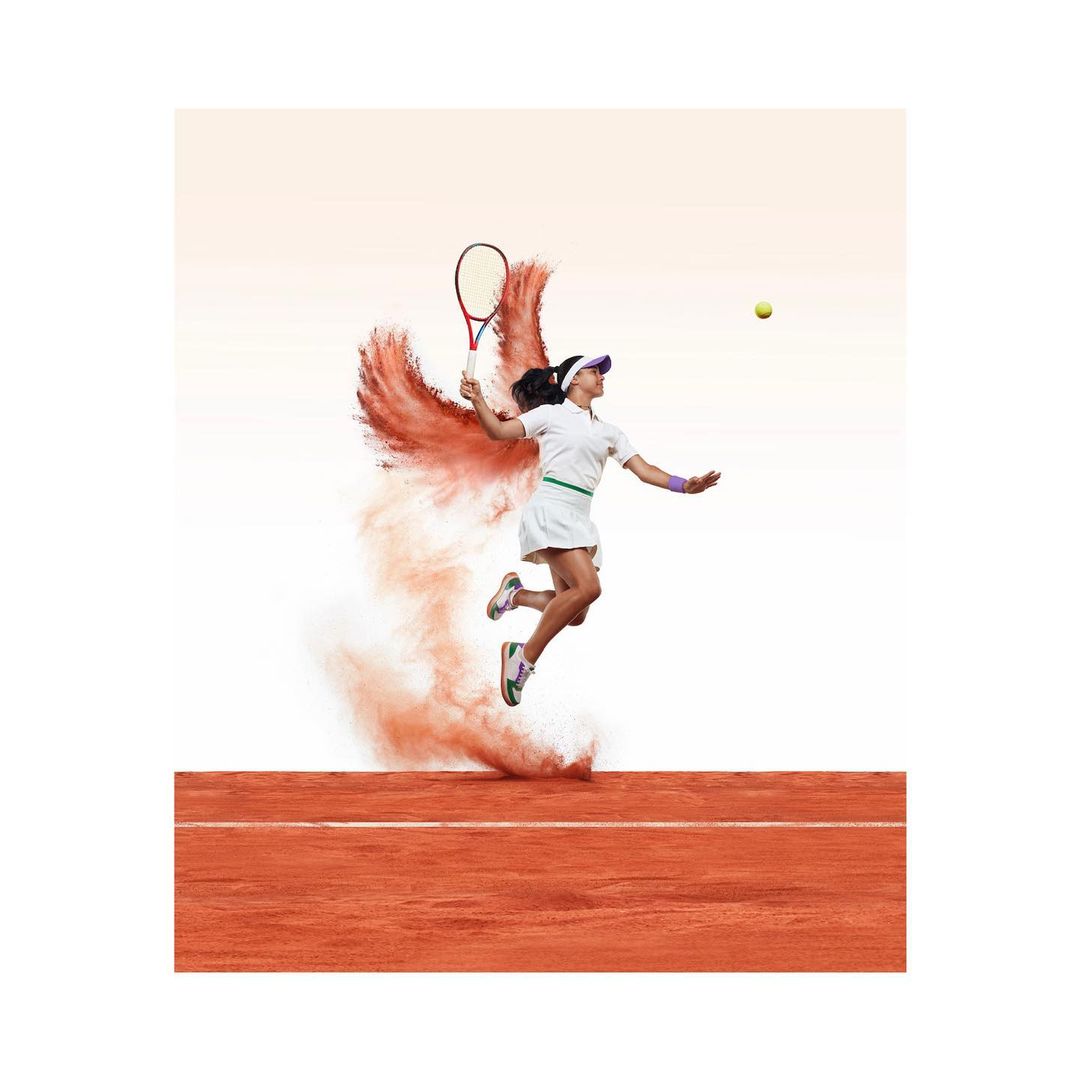 Female tennis player in mid-air serve on clay court with particle effect. Sports action shot with athlete, tennis racket, court details.